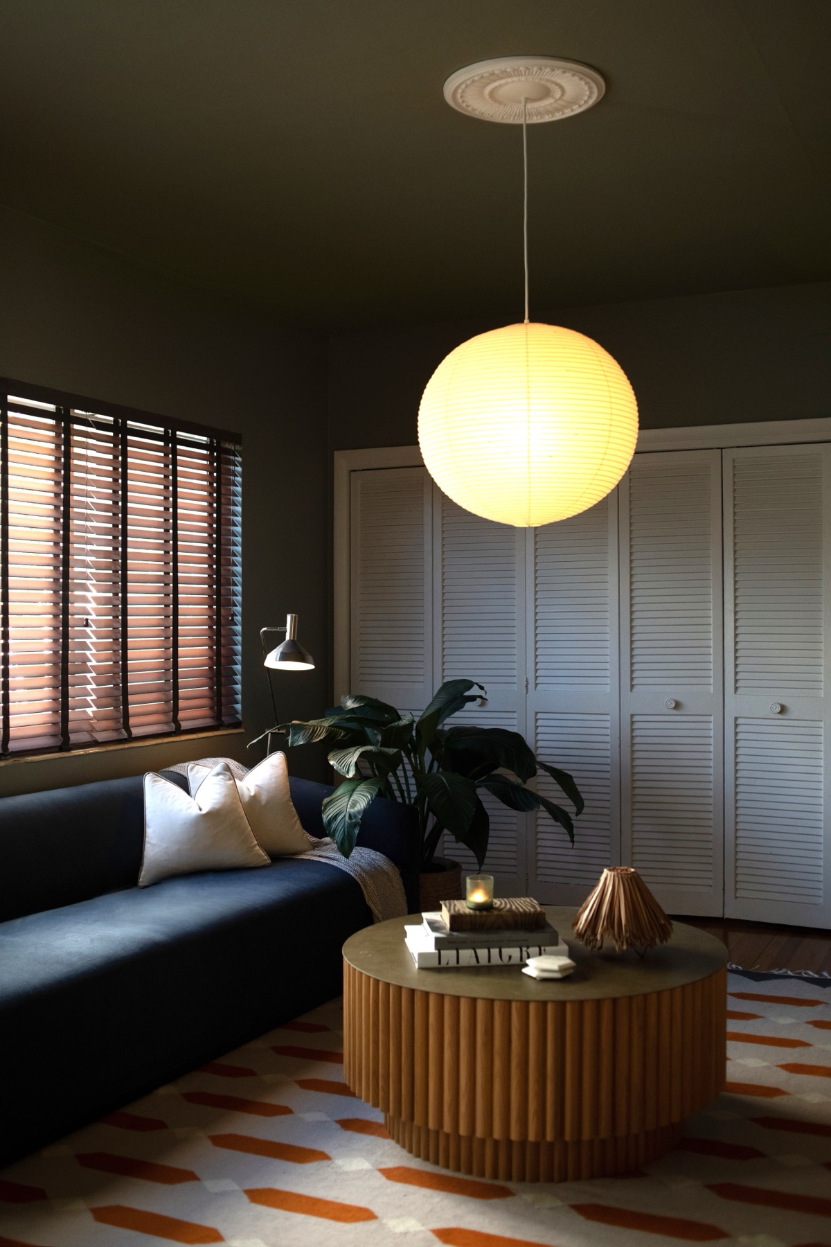 A living room by Studio DEA at 1140 Venetian Way: a paper lantern over a navy sofa, a fluted round coffee table and a patterned rug